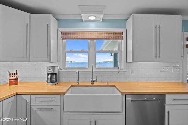 kitchen featuring butcher block counters, dishwasher, decorative backsplash, and a sink