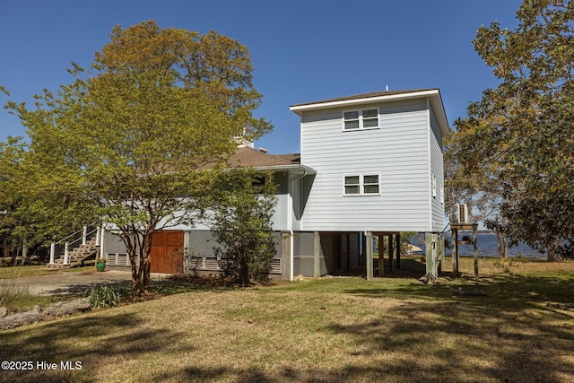 back of house with a carport and a lawn