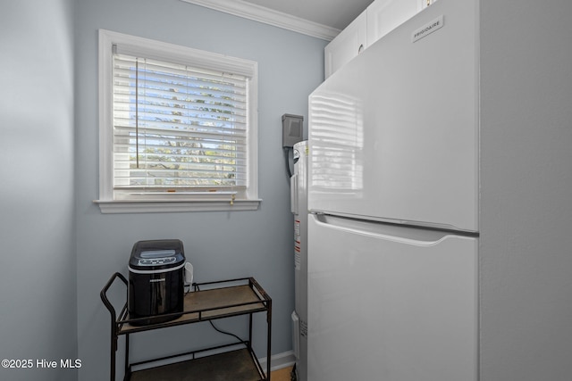 interior space featuring white cabinets, baseboards, freestanding refrigerator, and crown molding