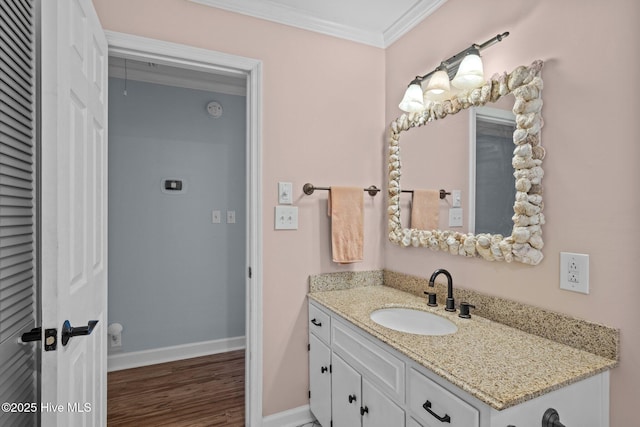 bathroom featuring wood finished floors, vanity, crown molding, and baseboards