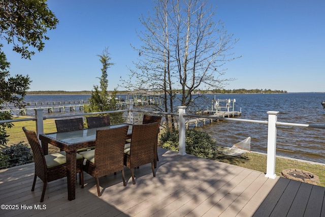 deck featuring outdoor dining area, boat lift, a water view, and a boat dock