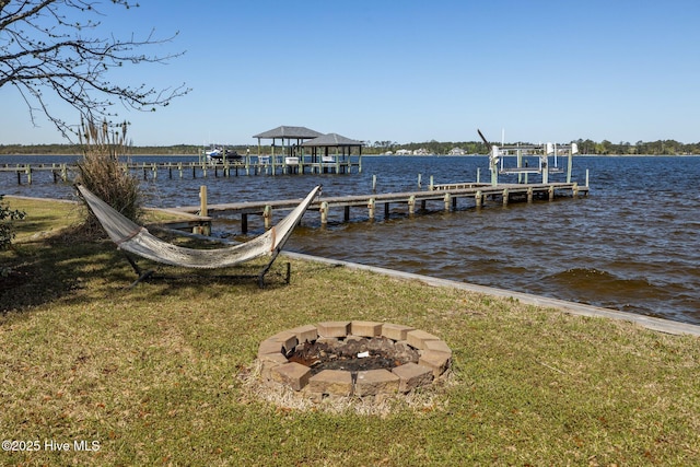 dock area with boat lift, a yard, an outdoor fire pit, and a water view