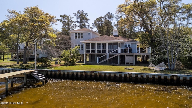 back of house featuring a lawn, a deck with water view, stairway, and a sunroom