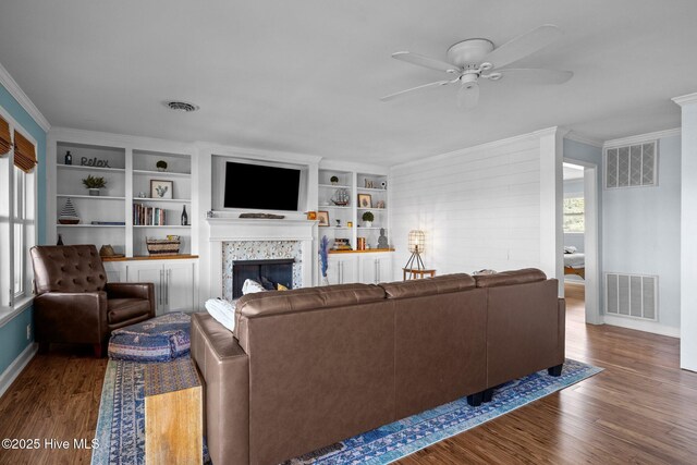 living room with crown molding, wood finished floors, visible vents, and a ceiling fan