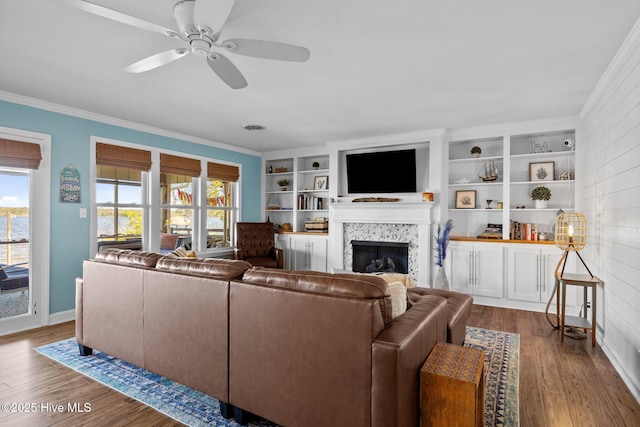 living area featuring a fireplace, dark wood finished floors, ornamental molding, and ceiling fan