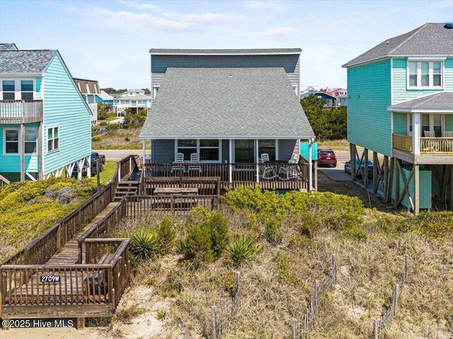 back of property featuring a residential view, a shingled roof, and a wooden deck