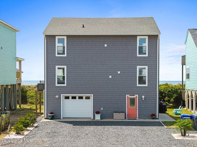 rear view of property featuring a garage and driveway