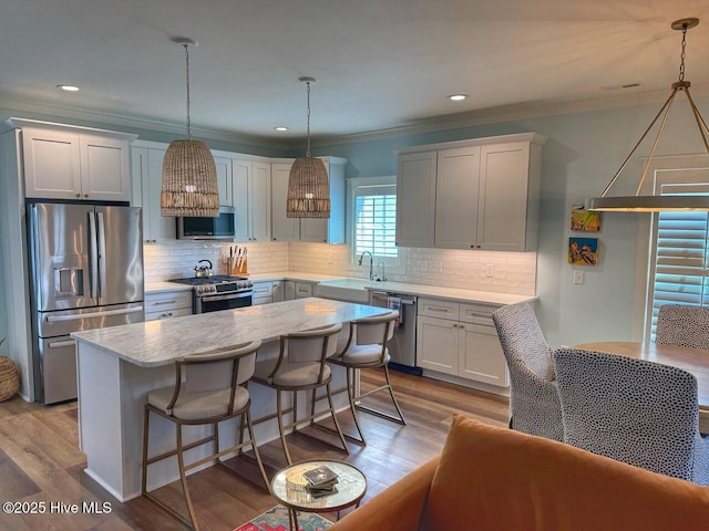 kitchen with a center island, stainless steel appliances, crown molding, and decorative backsplash