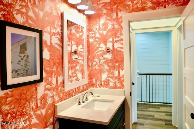 bathroom featuring vanity, wood finished floors, and wallpapered walls