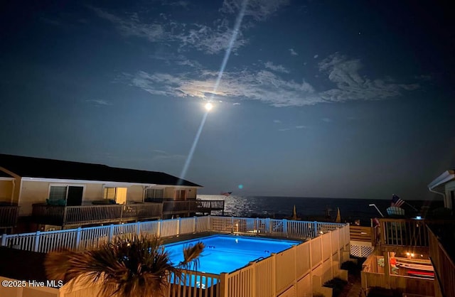 pool at twilight with a community pool and a water view