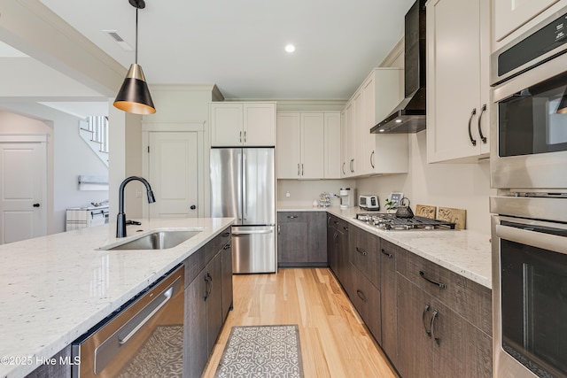 392 Blossom Tree Ln SE, Bolivia, NC 28422 - kitchen featuring appliances with stainless steel finishes, a sink, wall chimney range hood, light wood-style flooring, and dark brown cabinetry
