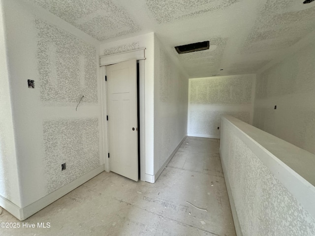 hall with baseboards and a textured ceiling