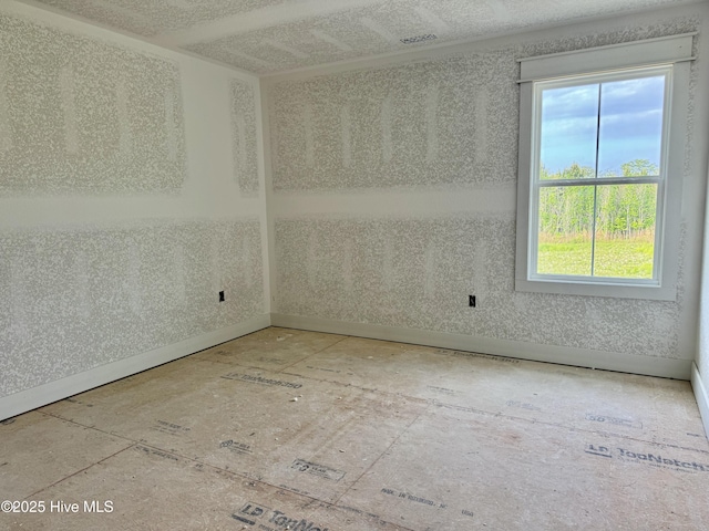 unfurnished room with baseboards and a wealth of natural light