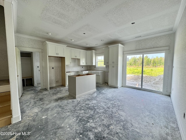 kitchen with a center island, ornamental molding, a textured ceiling, and white cabinetry