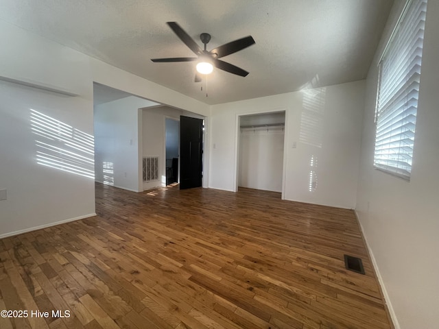 unfurnished bedroom featuring visible vents, baseboards, a closet, and hardwood / wood-style floors