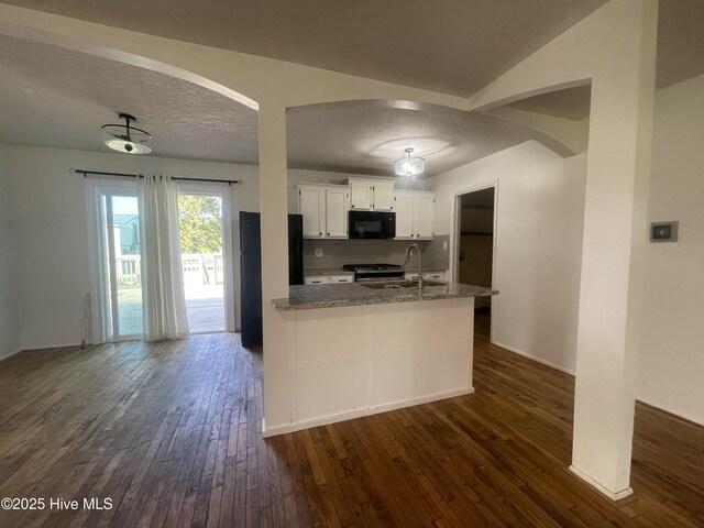 kitchen featuring arched walkways, black appliances, and dark wood finished floors