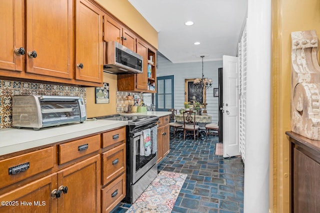 311 E Church St, Tarboro, NC 27886 - kitchen with an inviting chandelier, light countertops, brown cabinetry, stainless steel appliances, and stone finish flooring