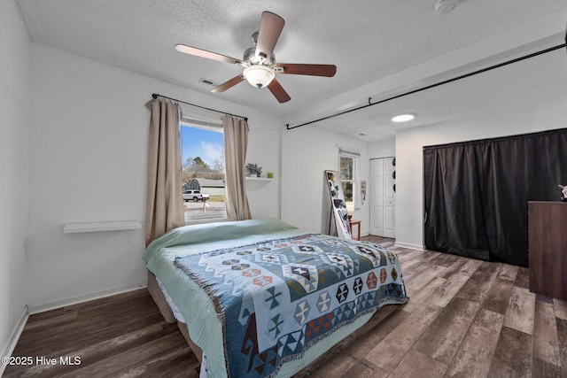 bedroom with a closet, a textured ceiling, baseboards, wood finished floors, and a ceiling fan
