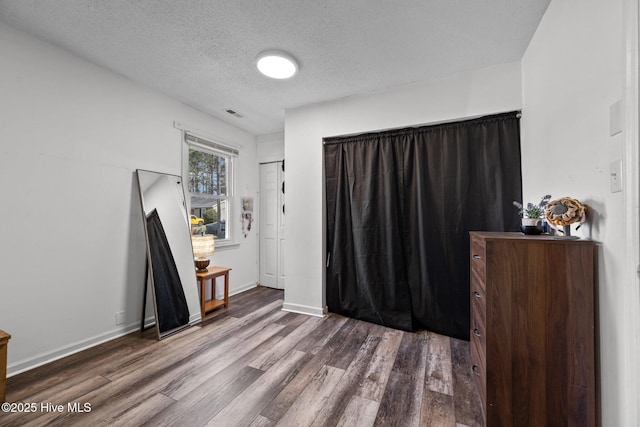 bedroom with baseboards, dark wood-style flooring, and a textured ceiling
