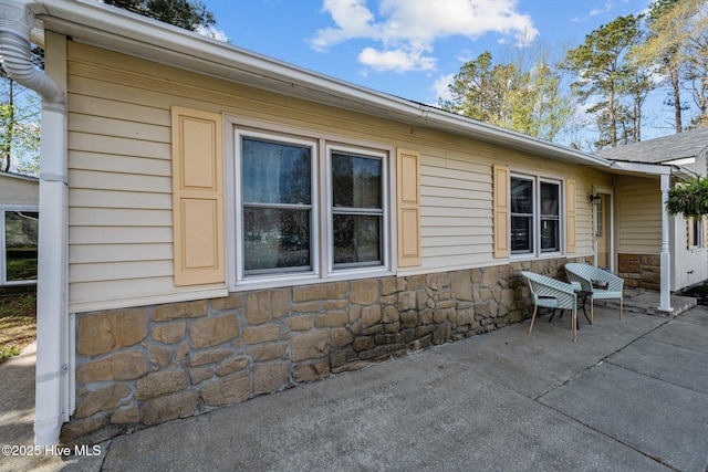 view of home's exterior with stone siding and a patio area