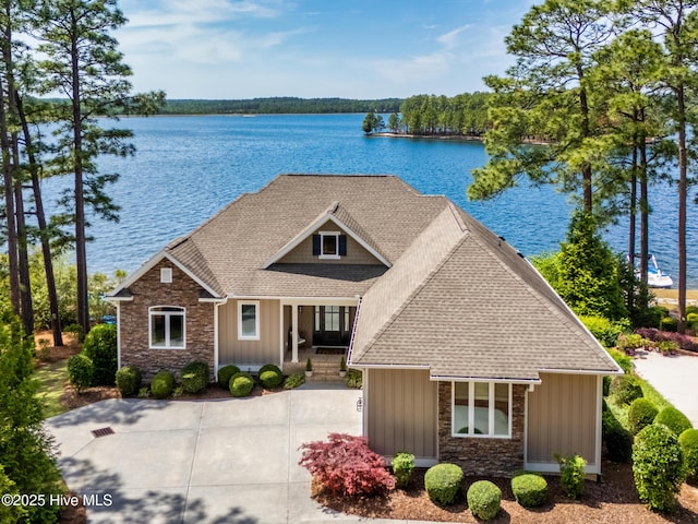 view of front of home featuring board and batten siding, a water view, a shingled roof, stone siding, and a porch