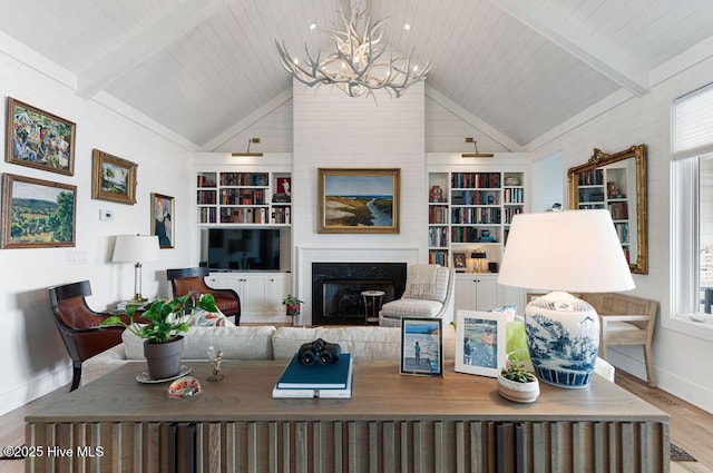 living room with a premium fireplace, baseboards, built in features, wood finished floors, and lofted ceiling with beams