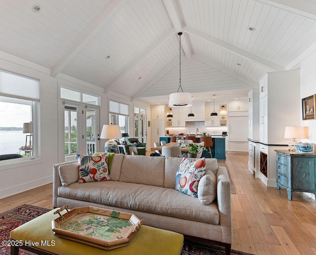 living area with light wood-style flooring, a wealth of natural light, and beam ceiling
