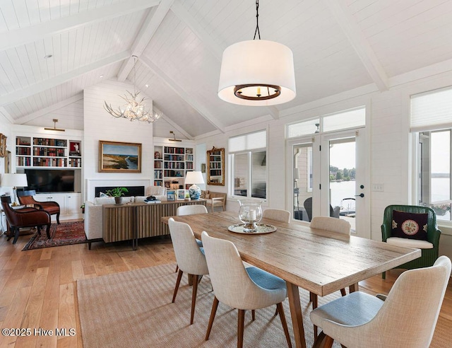 dining room featuring lofted ceiling with beams, built in features, an inviting chandelier, wood ceiling, and light wood-style floors