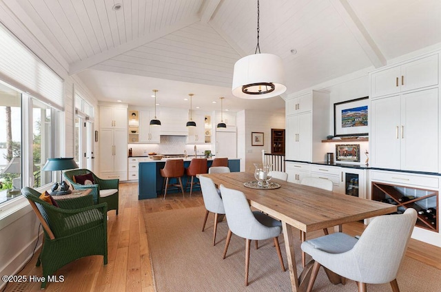 dining space with beamed ceiling, high vaulted ceiling, and light wood-style floors