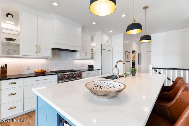 kitchen with a sink, decorative backsplash, high quality appliances, and white cabinets