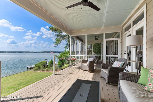 deck with a ceiling fan, a water view, a sunroom, and a lawn