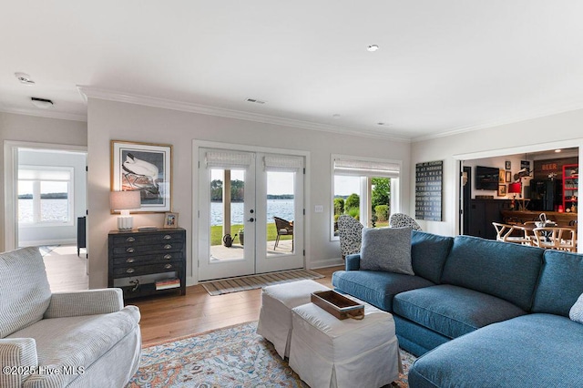 living area featuring wood finished floors, visible vents, french doors, and ornamental molding