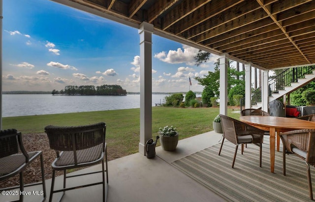 view of patio with outdoor dining area, a water view, and stairs