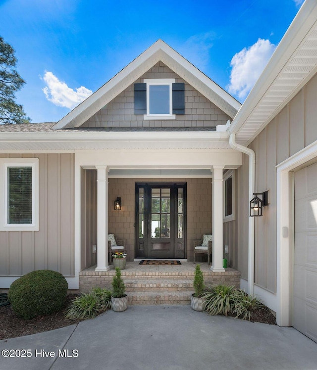 view of exterior entry with covered porch, board and batten siding, and a garage