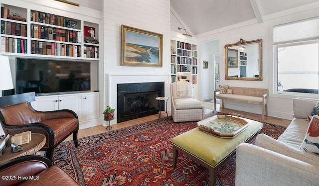 living area featuring lofted ceiling, a high end fireplace, built in features, and wood finished floors