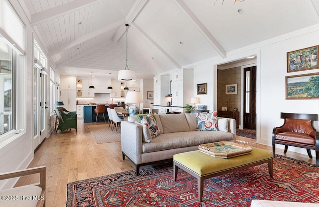 living room featuring beam ceiling, light wood-style flooring, a healthy amount of sunlight, and high vaulted ceiling