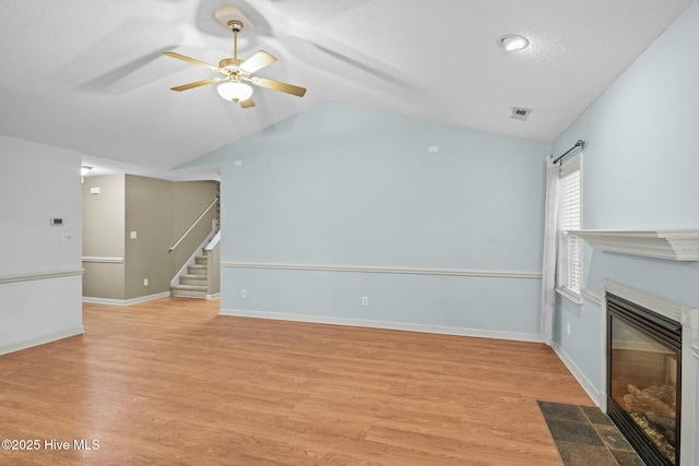 301 Derby Park Ave, New Bern, NC 28562 - unfurnished living room with visible vents, stairs, lofted ceiling, ceiling fan, and a fireplace with flush hearth