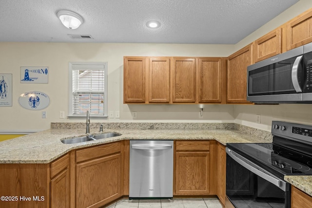 301 Derby Park Ave, New Bern, NC 28562 - kitchen featuring appliances with stainless steel finishes, light stone counters, a sink, a textured ceiling, and visible vents