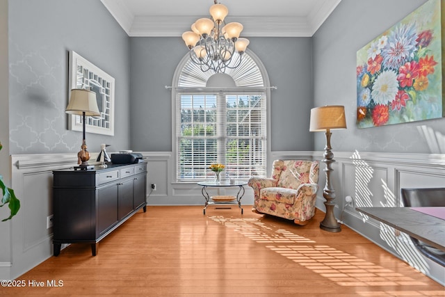 sitting room featuring an inviting chandelier, wainscoting, ornamental molding, and light wood-style floors