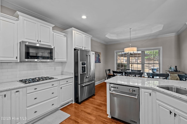 kitchen with backsplash, white cabinets, appliances with stainless steel finishes, and light wood-type flooring