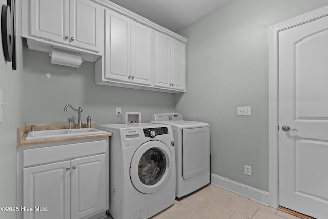 clothes washing area featuring cabinet space, a sink, baseboards, light tile patterned floors, and washing machine and dryer