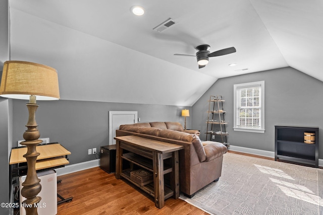 interior space with ceiling fan, baseboards, wood finished floors, vaulted ceiling, and visible vents
