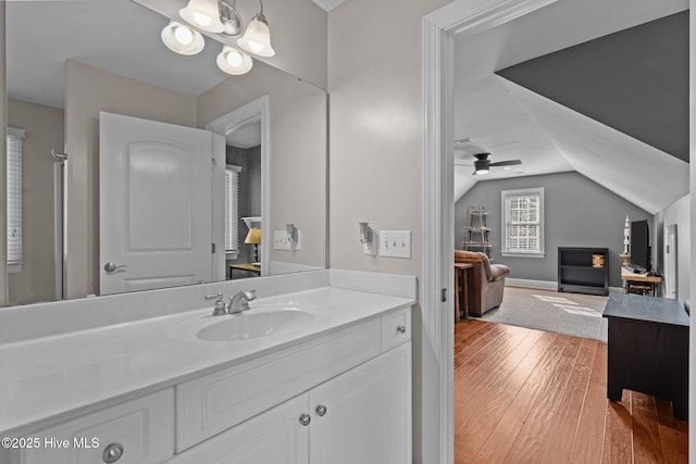bathroom featuring ceiling fan, vanity, hardwood / wood-style floors, baseboards, and vaulted ceiling