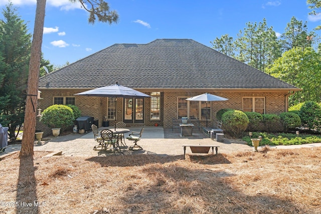 rear view of house featuring french doors, a shingled roof, a patio area, and brick siding