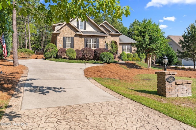 view of front of home with brick siding, driveway, and a front yard