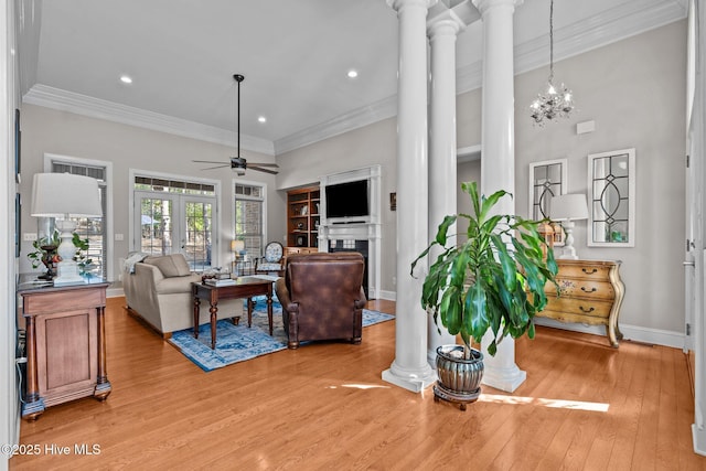 living room featuring baseboards, decorative columns, ceiling fan with notable chandelier, and light wood finished floors