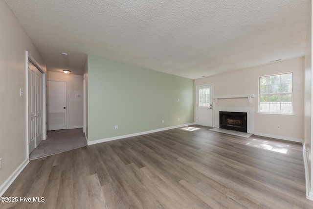 3002 E Windgate Ct, Jacksonville, NC 28546 - unfurnished living room featuring baseboards, a textured ceiling, wood finished floors, and a tiled fireplace