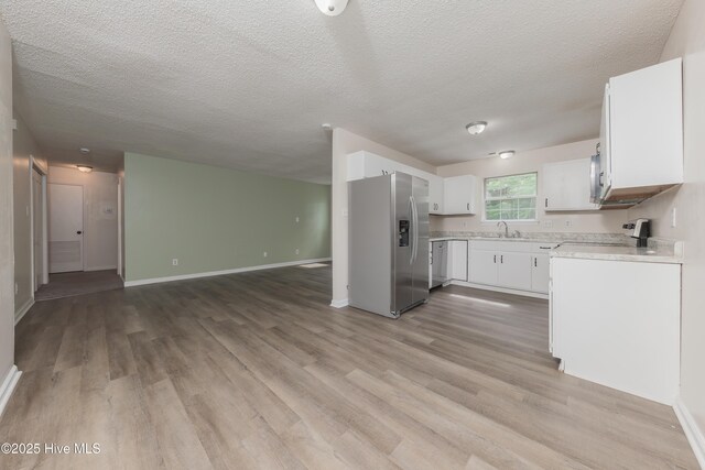 3002 E Windgate Ct, Jacksonville, NC 28546 - kitchen featuring light countertops, a sink, open floor plan, stainless steel appliances, and light wood-style floors