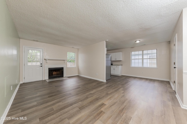 3002 E Windgate Ct, Jacksonville, NC 28546 - unfurnished living room featuring baseboards, dark wood-style flooring, a fireplace, and a textured ceiling