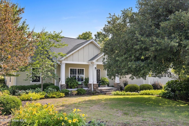 5994 Gray Squirrel Path, Southport, NC 28461 - craftsman-style home featuring board and batten siding, a front yard, stone siding, a shingled roof, and a porch